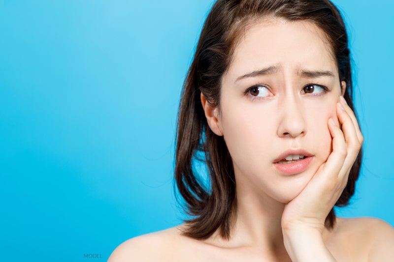 Girl holding jaw because of pain.