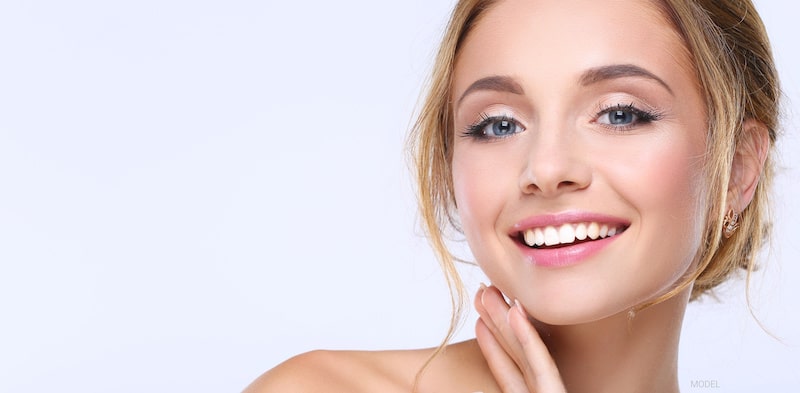 A pretty woman with a beautiful smile against a light violet background.