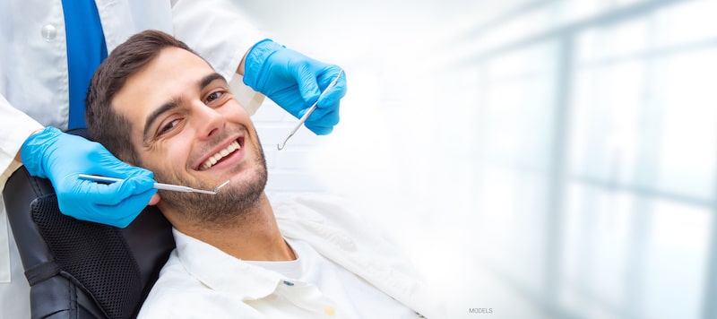 A man smiles while receiving dental care.